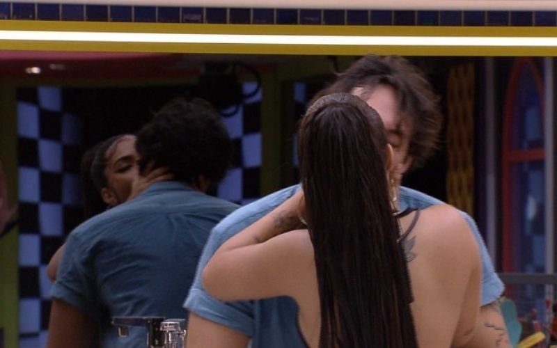 Mari e Eli se beijam na cozinha na festa Jogos.