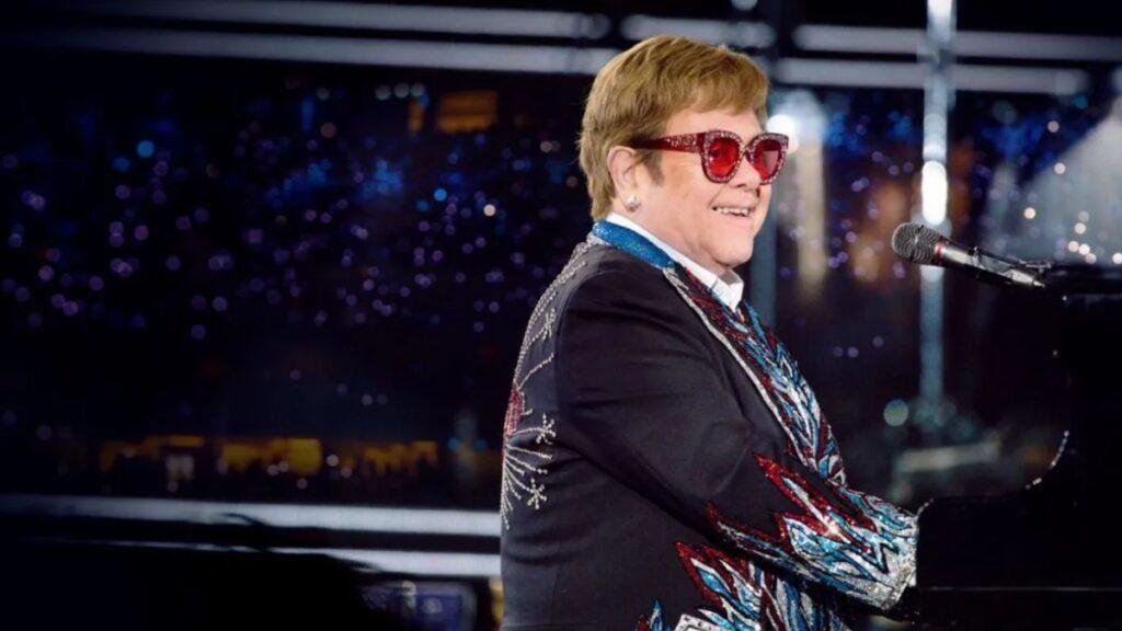 Elton John, EGOT, tocando piano em apresentação.