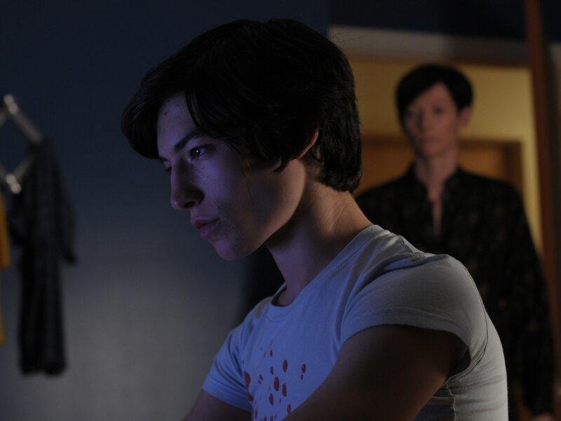 Ezra Miller sentado em frente computador e Tilda Swinton parada na porta olhando para frente, um dos filmes inspirados em livros de suspense.
