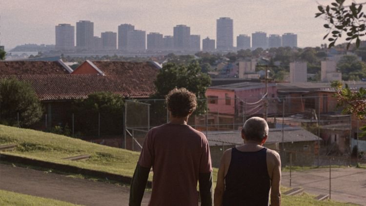 Cena do filme Futuro Futuro onde estão o protagonista e outro personagem, olhando a cidade ao fundo
