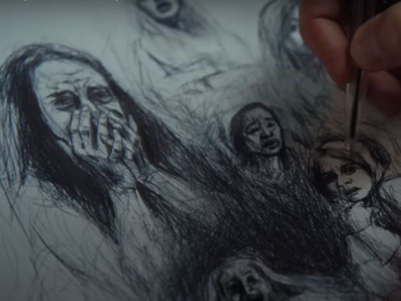 Mão desenhando rosto de mulheres em folha de papel