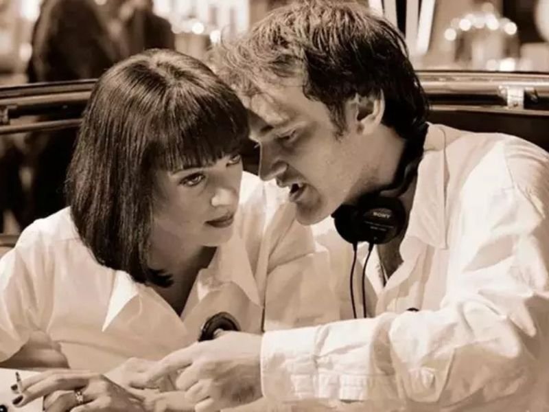 Quentin Tarantino orienta atriz em bastidores de filmagem, cena que representa o estilo criativo explorado no documentário "Escrito e Dirigido por Quentin Tarantino".