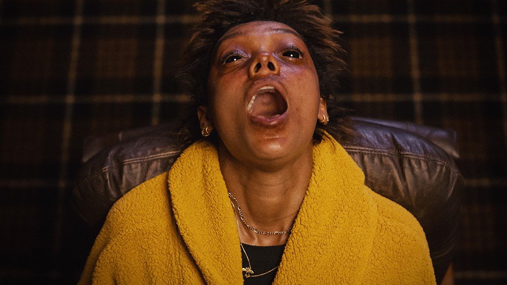 A atriz Sophie Wilde com o rosto tomado por marcas e a boca aberta em transe, em uma cena dramática do que muitos apontam como o melhor filme de terror da A24.