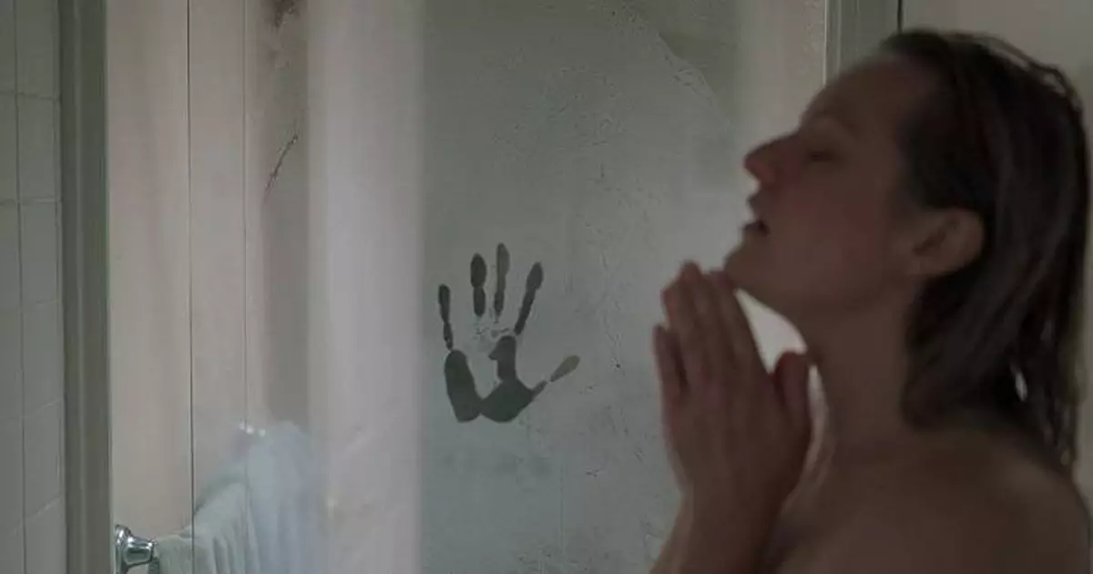 Elisabeth Moss com as mãos juntas no rosto em frente a um vidro com uma marca de mão suja, representando o suspense de um aclamado filme que disputa o posto de melhor filme de terror.