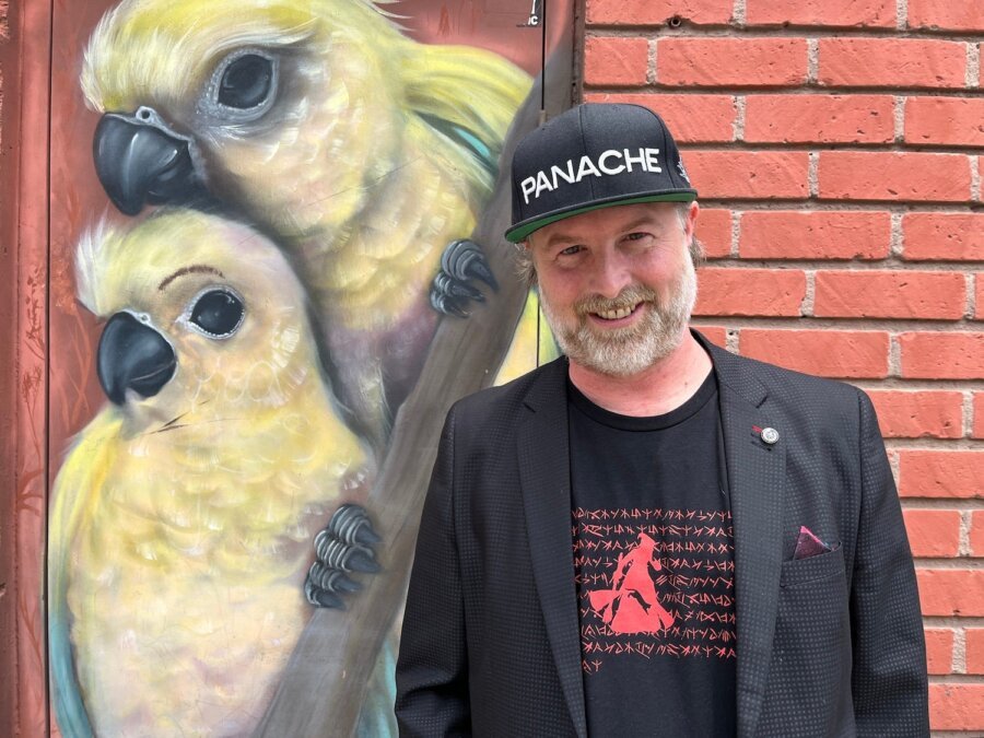 O diretor criativo Patrice Désilets posando com um boné da Panache e camiseta temática.