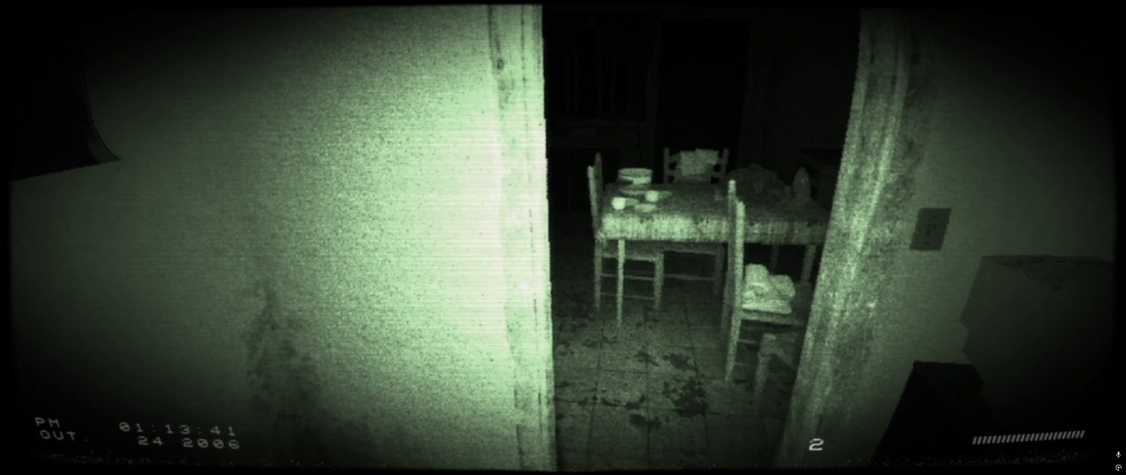 Passagem para uma cozinha com mesa, cadeiras e eletrodomésticos, sob visão noturna.