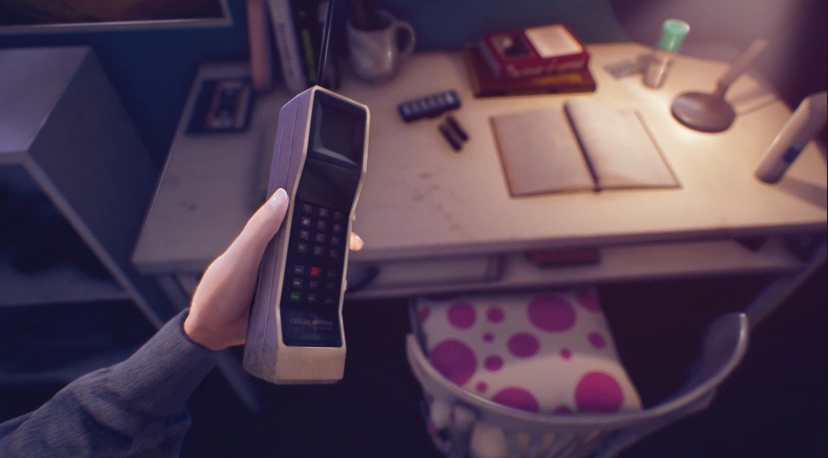 Mão segurando um telefone diante de uma mesa com livros e luminária em The Suicide of Rachel Foster.