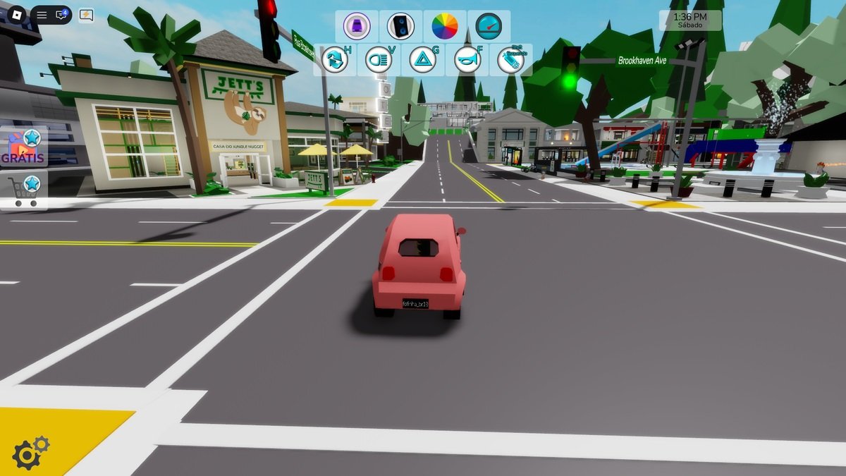 Carro rosa em uma rua de Brookhaven, com estabelecimentos e uma praça ao fundo.